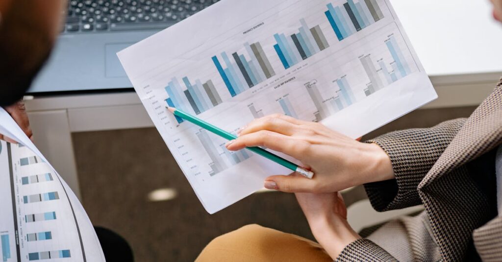 pexels photo 7691704 7691704 Two adults discuss financial data with charts and laptop in office setting.